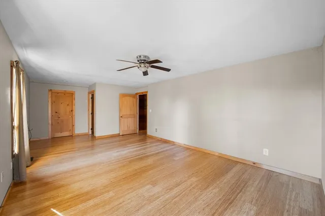 a view of an empty room with window and wooden floor
