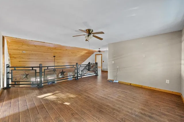 an empty room with wooden floor and a ceiling fan