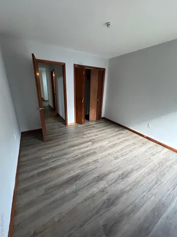a view of an empty room with closet and wooden floor
