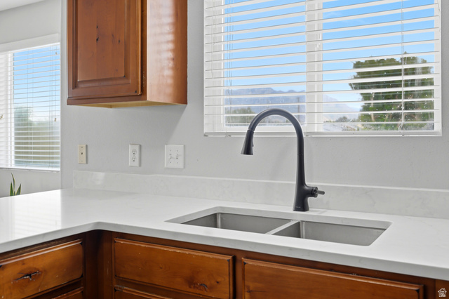 116 East Resaca Drive, Unit F6 Sandy, UT 84070 - Photo 14 of 32 Kitchen featuring a stainless steel double basin sink with a matte black gooseneck faucet, white solid surface countertops, light wood-finish cabinetry, and a window with horizontal blinds