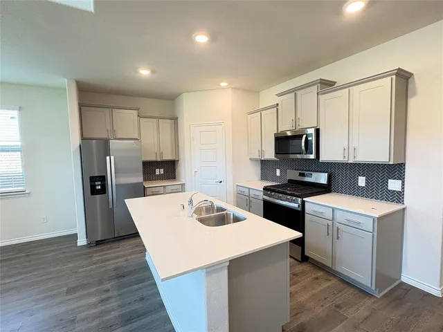 a kitchen with a refrigerator a stove top oven a sink and cabinets