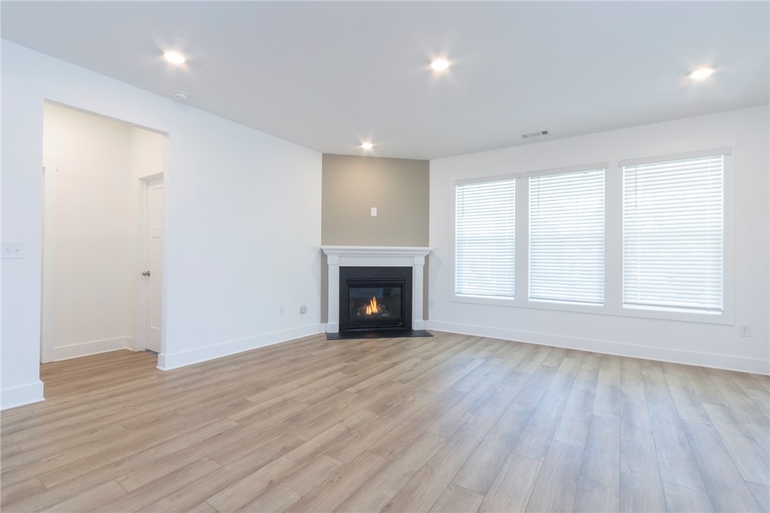 607 WH Kay Lane Anderson, SC 29621 - Photo 4 of 48 A comforting fireplace anchors this spacious living area, illuminated by recessed lighting and natural light from wide windows.