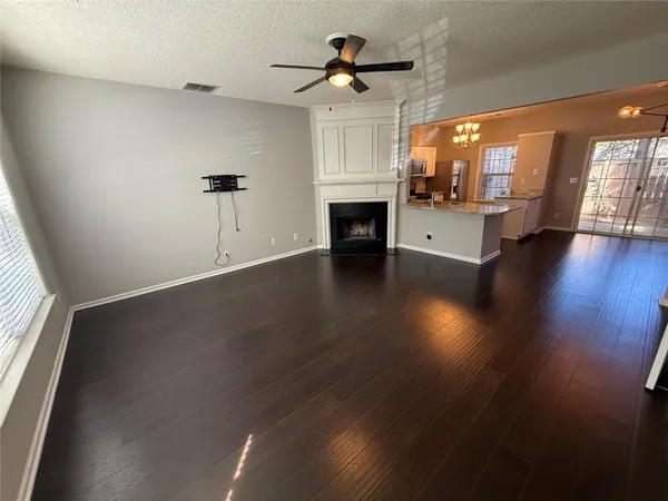 a view of a livingroom with a fireplace a window and wooden floor