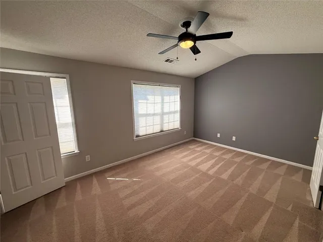 an empty room with windows and ceiling fan