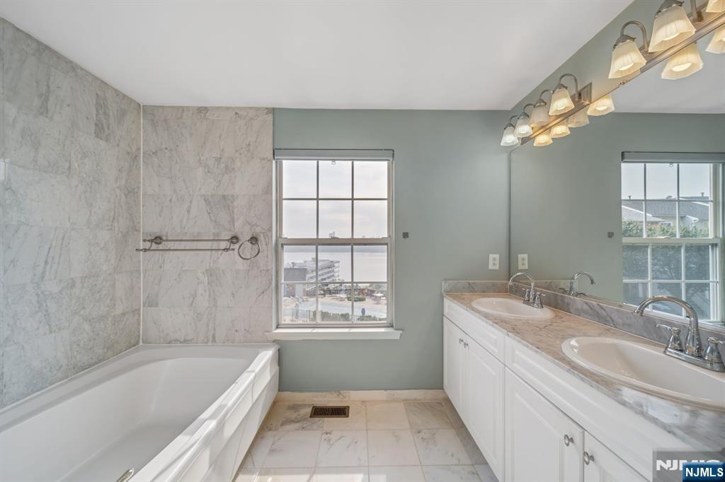 66 Bergen Ridge Road, Unit 1 North Bergen, NJ 07047 - Photo 18 of 26 a bathroom with a granite countertop bathtub a sink and a large mirror