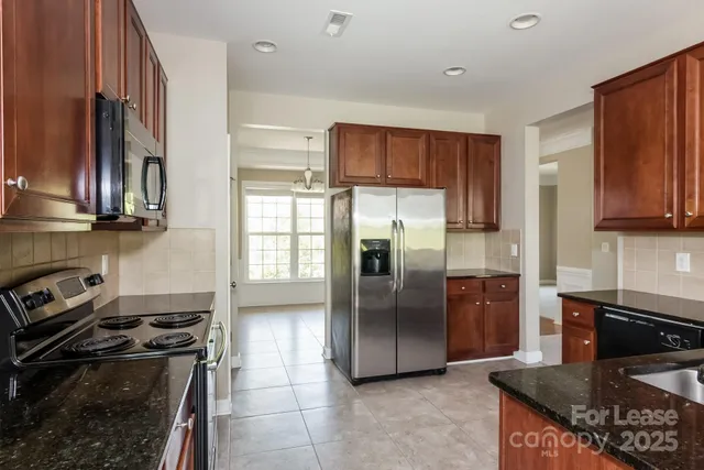 a kitchen with stainless steel appliances granite countertop a stove a refrigerator and a sink