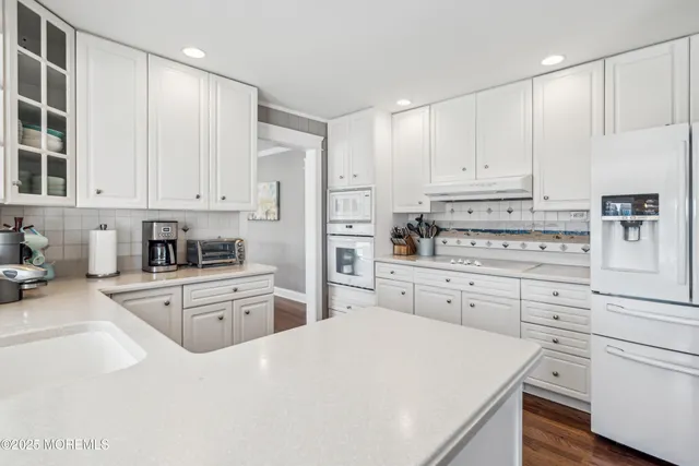 a kitchen with granite countertop white cabinets and stainless steel appliances