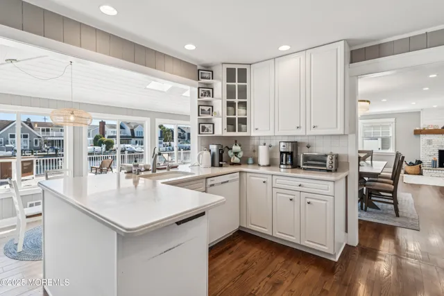 a kitchen with granite countertop a stove a sink and white cabinets with wooden floor