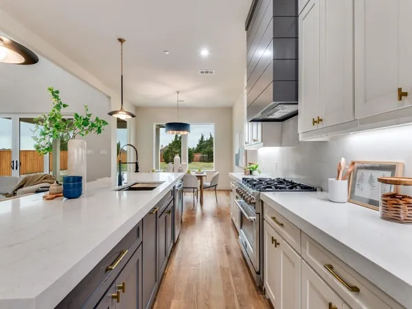 a kitchen with stainless steel appliances granite countertop a sink a stove and a wooden floors