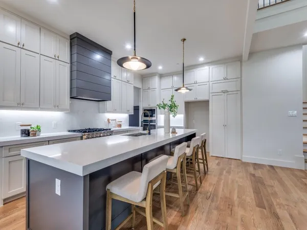 a kitchen with stainless steel appliances granite countertop a sink a stove a refrigerator and island with wooden floor