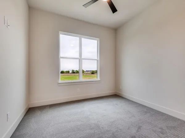 an empty room with windows and ceiling fan