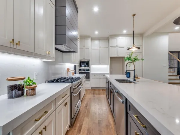 a kitchen with stainless steel appliances granite countertop a sink a stove and a wooden floors