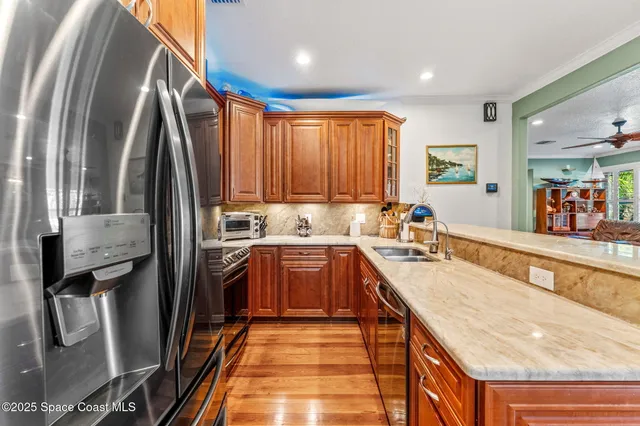 a kitchen with stainless steel appliances granite countertop a refrigerator a sink and wooden cabinets