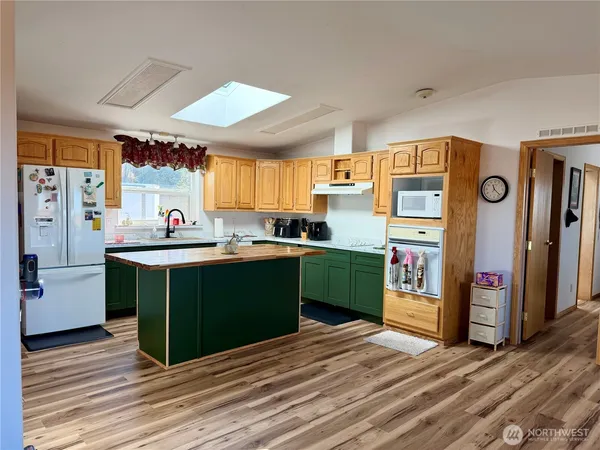 a kitchen with stainless steel appliances kitchen island granite countertop a refrigerator a sink dishwasher a stove and a dining table with wooden floor