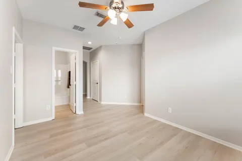 an empty room with chandelier fan and windows