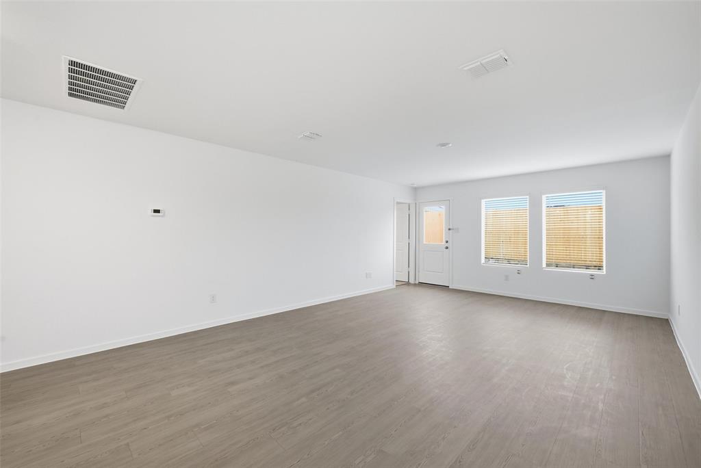1037 Raintree Road Princeton, TX 75407 - Photo 7 of 21 an empty room with wooden floor and windows