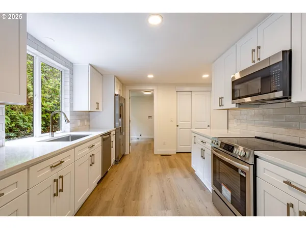 a kitchen with stainless steel appliances granite countertop a stove a sink dishwasher a refrigerator and a microwave oven with wooden floor