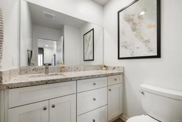 a bathroom with a granite countertop sink a toilet and a mirror