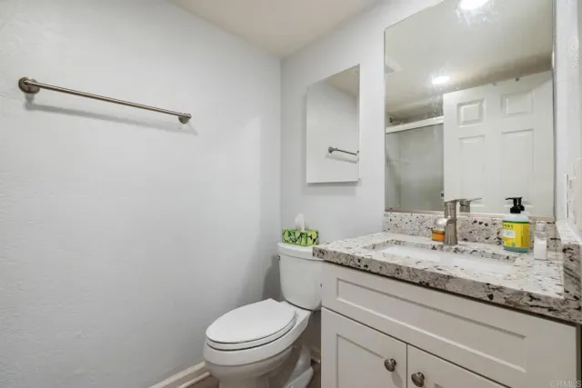 a bathroom with a granite countertop toilet sink and mirror