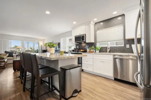 a kitchen with stainless steel appliances granite countertop a table chairs sink and cabinets