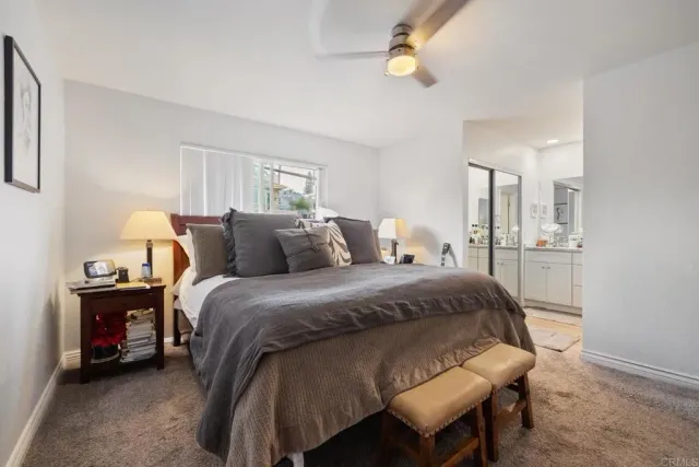 a bed sitting in a bedroom next to a window with a lamp and a chandelier