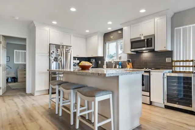 a kitchen with stainless steel appliances granite countertop a stove top oven a refrigerator a sink and a dining table with wooden floor