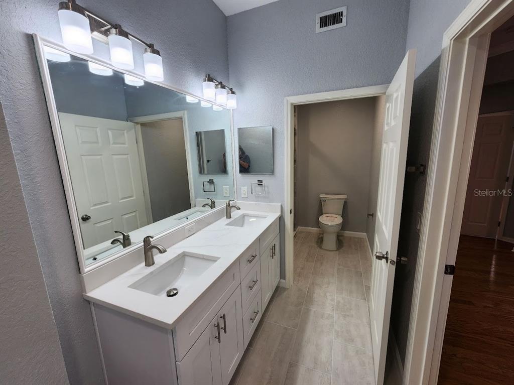 7511 Bayport Road, Unit 5 Orlando, FL 32819 - Photo 11 of 26 a bathroom with a double vanity sink and mirror