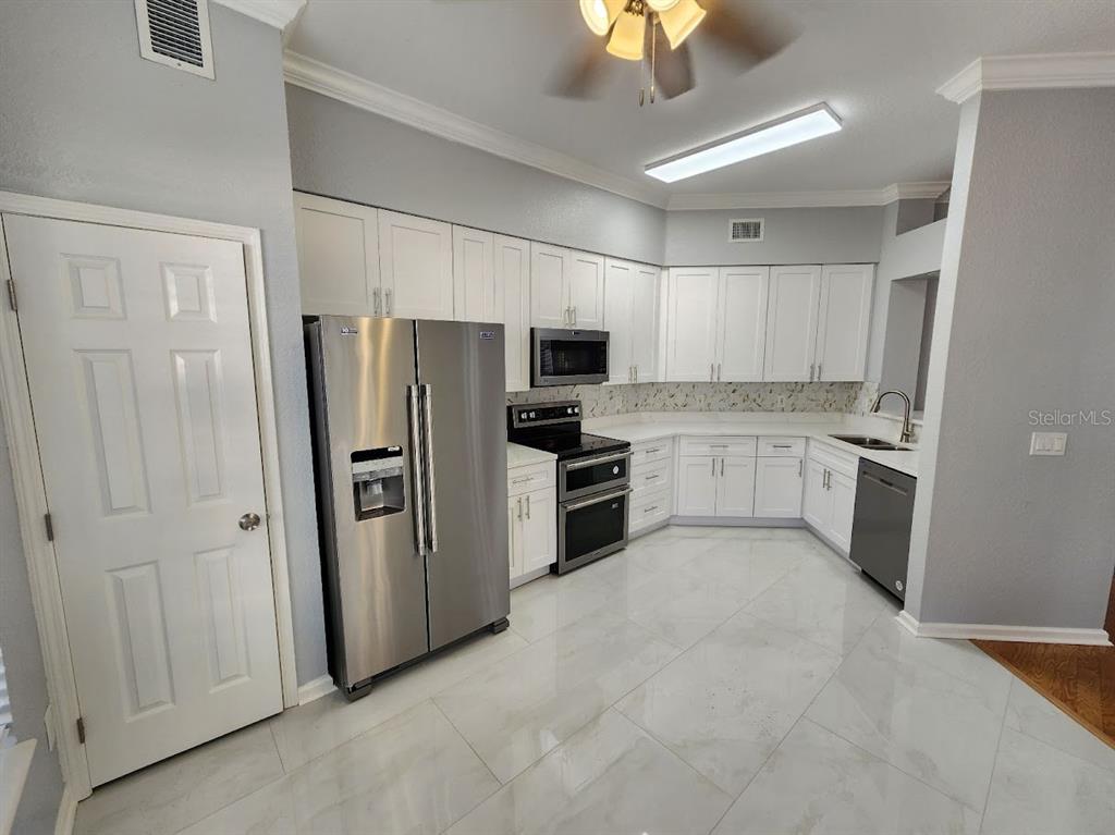 7511 Bayport Road, Unit 5 Orlando, FL 32819 - Photo 2 of 26 a large kitchen with cabinets and stainless steel appliances