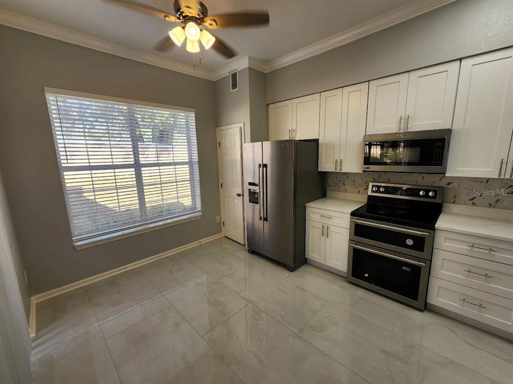 7511 Bayport Road, Unit 5 Orlando, FL 32819 - Photo 3 of 26 a kitchen with stainless steel appliances a refrigerator stove and microwave