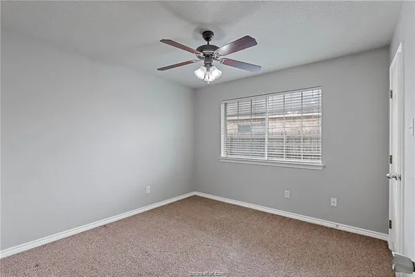 an empty room with a window and a fan