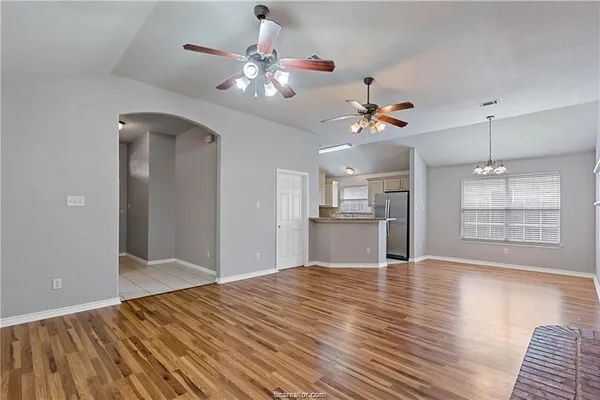 a view of an empty room with window and wooden floor