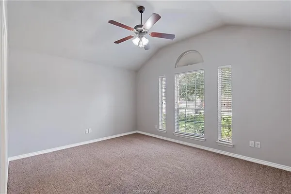 an empty room with windows and ceiling fan