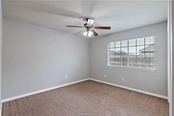an empty room with a window and a fan