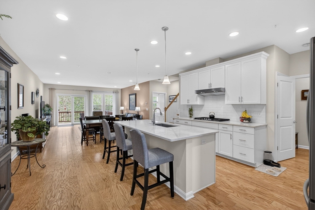 87 Shannon Way, Unit 86 Upton, MA 01568 - Photo 13 of 36 a kitchen with stainless steel appliances kitchen island granite countertop a stove a sink a refrigerator and white cabinets with wooden floor