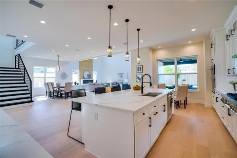 a large white kitchen with lots of counter space wooden floor and appliances
