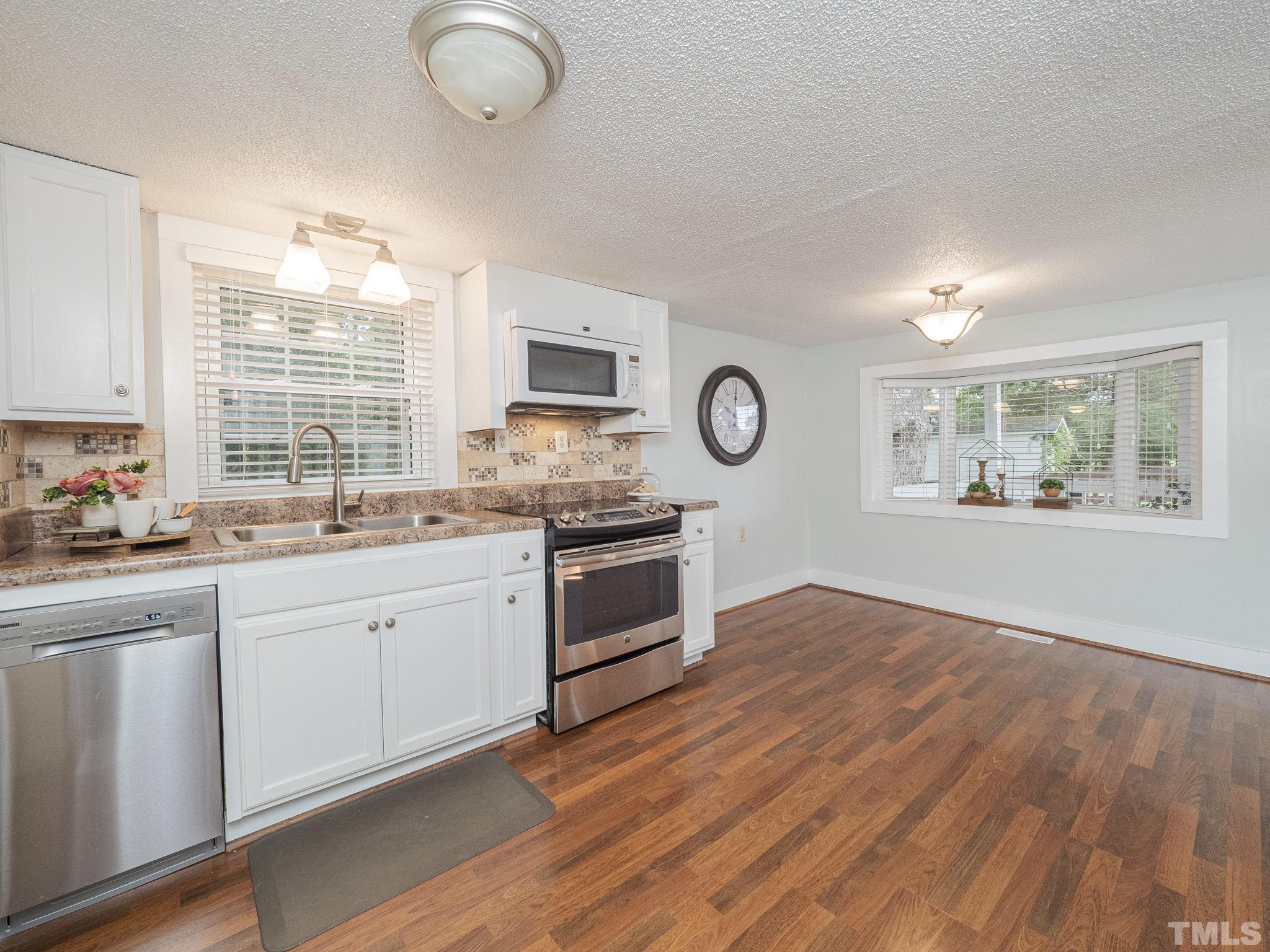 4821 Purnell Road Wake Forest, NC 27587 - Photo 14 of 19 a kitchen with stainless steel appliances granite countertop a stove a sink and a large window