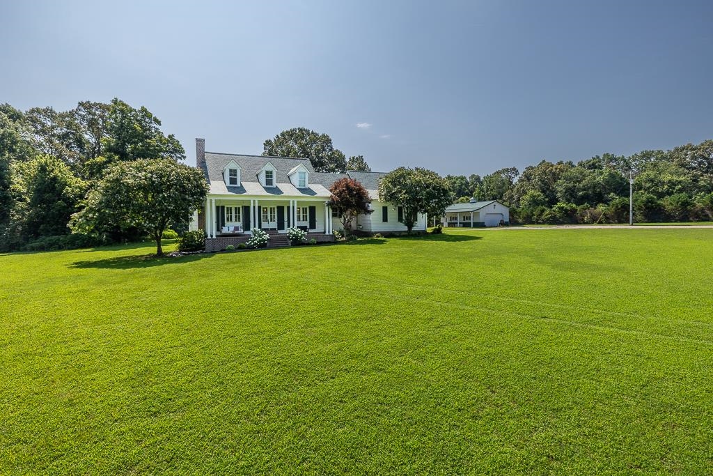 1915 Teague Store Road Somerville, TN 38068 - Photo 4 of 38 Expansive green lawn with a white colonial-style home featuring a covered front porch with white columns, dark shutters, and three dormer windows
