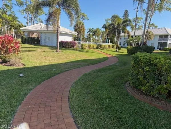 a view of a house with a big yard and palm trees