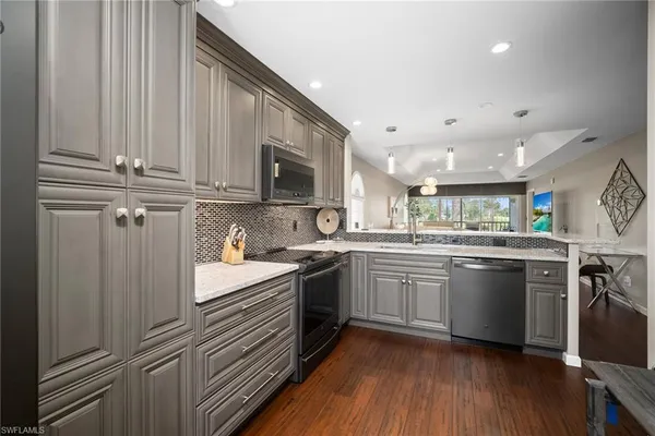 a kitchen with stainless steel appliances granite countertop a sink a stove a refrigerator cabinets and a window