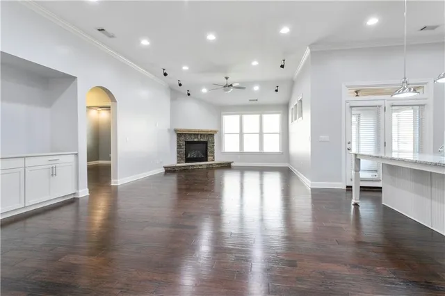 a view of empty room with wooden floor and kitchen view