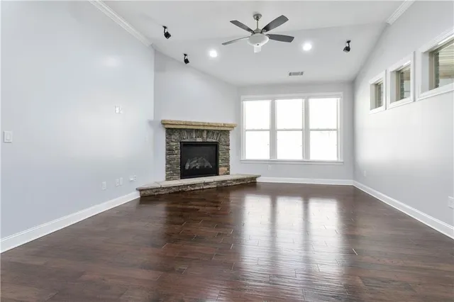 an empty room with wooden floor fireplace and windows