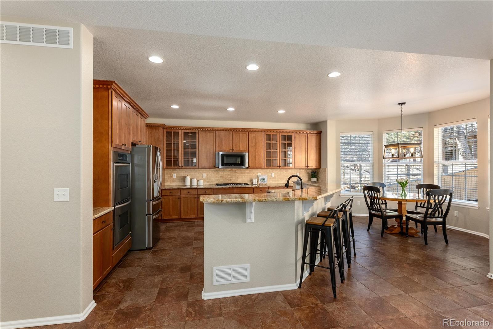 10820 Montvale Circle Highlands Ranch, CO 80130 - Photo 8 of 50 a kitchen with a table chairs refrigerator and microwave