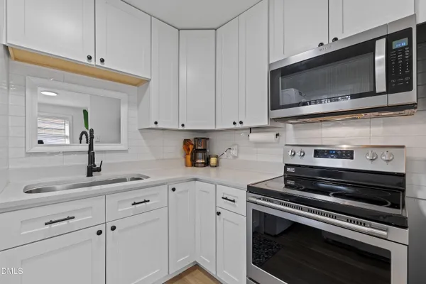 a kitchen with granite countertop white cabinets and white stove