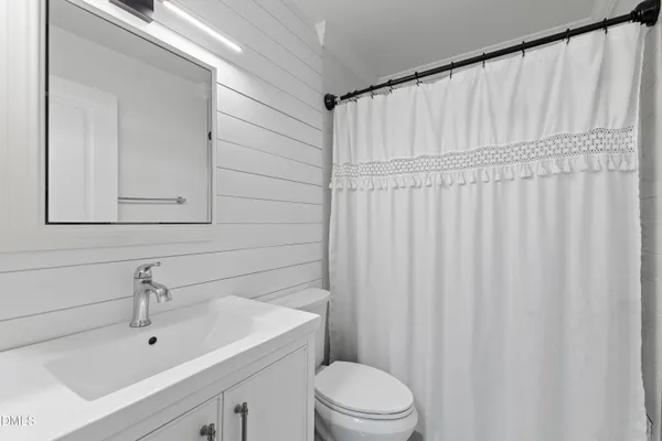 a bathroom with a white sink a toilet a shower curtain and a mirror