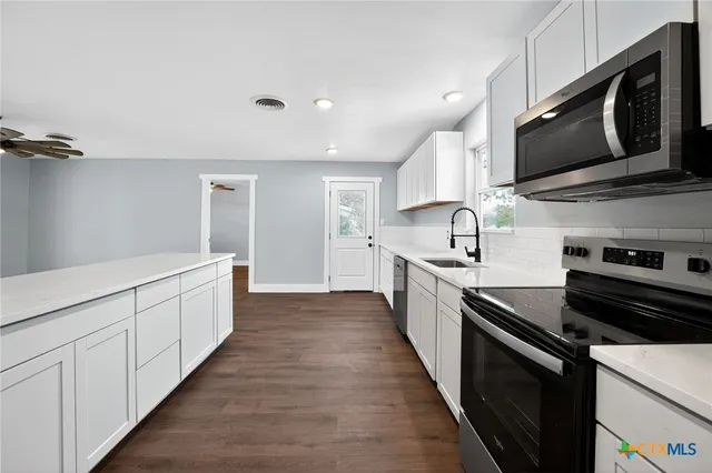 a large kitchen with stainless steel appliances kitchen island granite countertop a stove a sink and a microwave