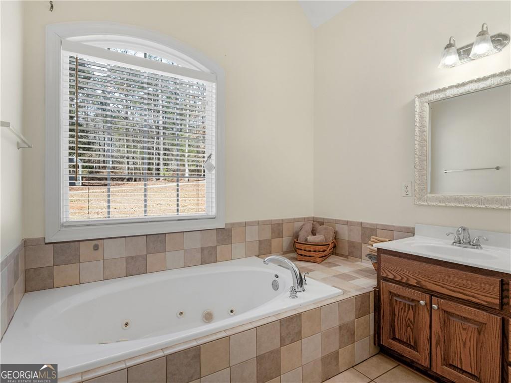 355 Parker Road Covington, GA 30014 - Photo 47 of 60 a bathroom with a bathtub a sink a vanity and a window