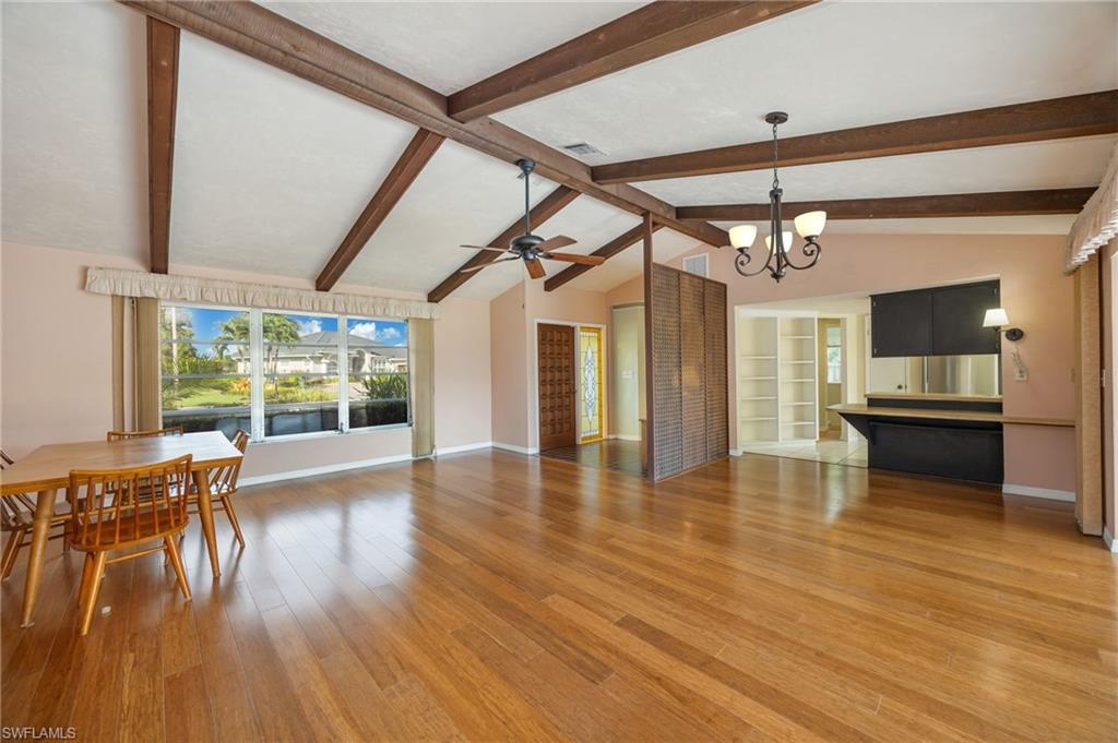 379 Torrey Pines Point Naples, FL 34113 - Photo 4 of 21 Vaulted ceilings with exposed beams, wood-finish flooring, a built-in desk with overhead cabinetry, and a multi-pane window