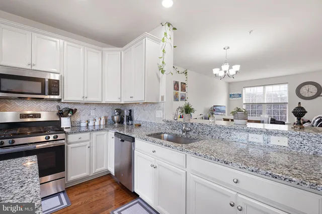 a kitchen with granite countertop a sink a stove and cabinets