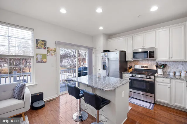 a kitchen with granite countertop kitchen island stainless steel appliances a stove a sink a refrigerator cabinets and dining table