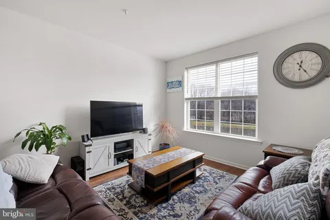 a living room with furniture a flat screen tv and a window